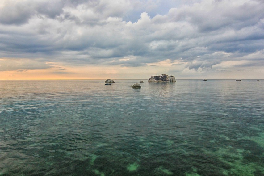 Memandangi laut yang tenang dari atas batu granit di Pantai Tanjung Tinggi dapat menghilangkan kepenatan segala rutinitas