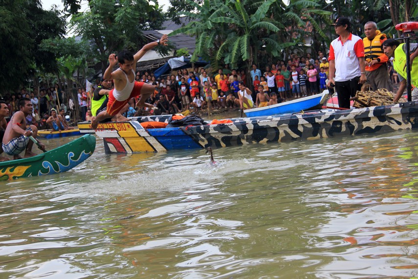 Seorang peserta melompat dari perahu untuk mendapatkan bebek yang dilepas dalam tradisi lempar bebek