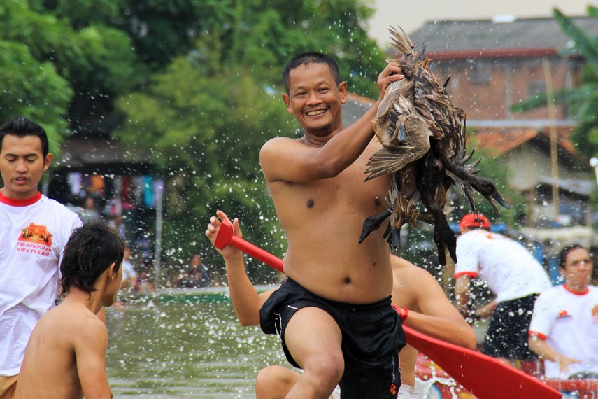 Wajah gembira seorang peserta yang berhasil menangkap bebek dalam tradisi lempar bebek Sungai Cisadane