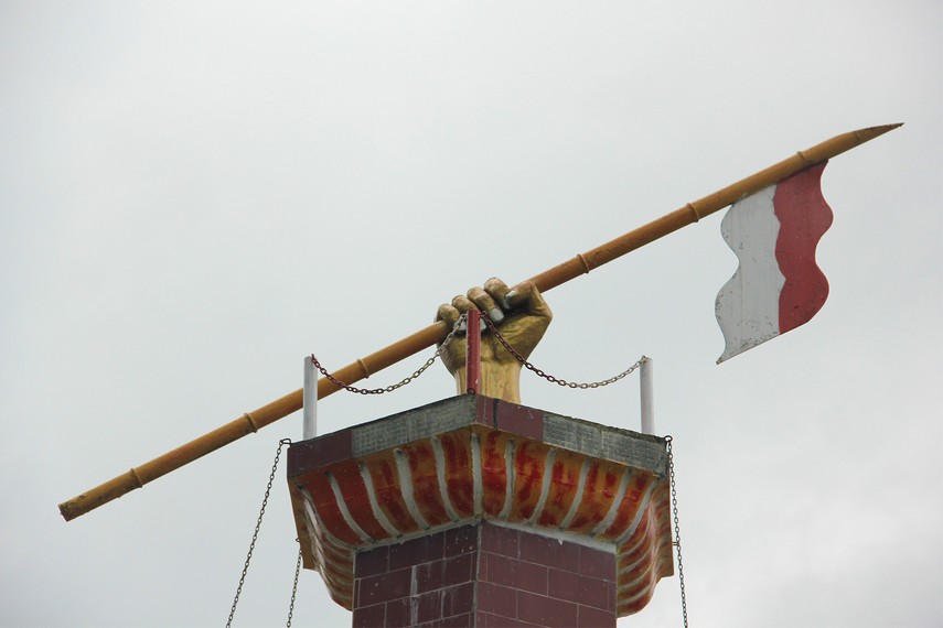 Pada bagian atas menara terdapat bentuk tangan manusia sedang mengepal bendera sebagai lambang perjuangan