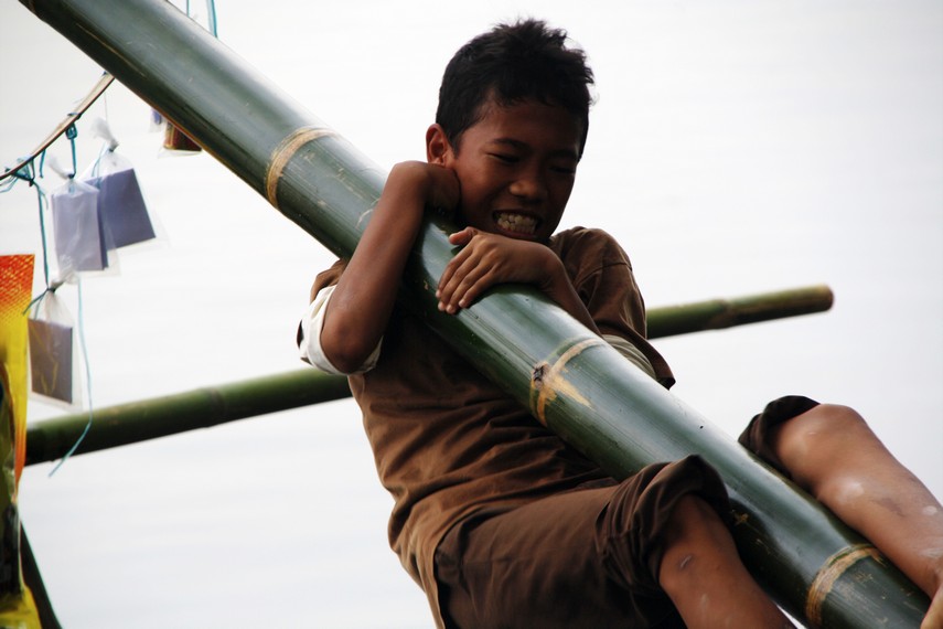 Ekspresi seorang anak ketika berusaha mencapai puncak pohon pinang