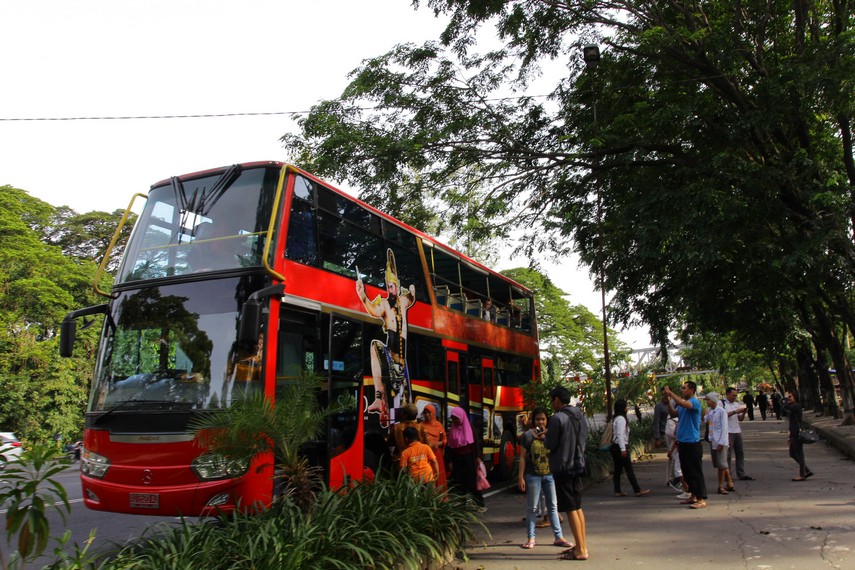 Penumpang mengabadikan momen berada di atas bus wisata werkudara saat berhenti di depan Taman Makam Pahlawan Solo