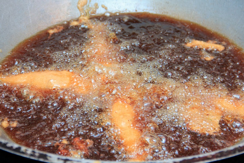 Ikan yang sudah diselimuti adonan tepung digoreng dengan minyak panas