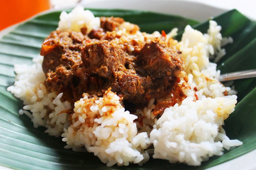 Sepiring nasi putih yang disajikan dengan potongan daging sapi yang empuk dan disiram dengan kuah kental